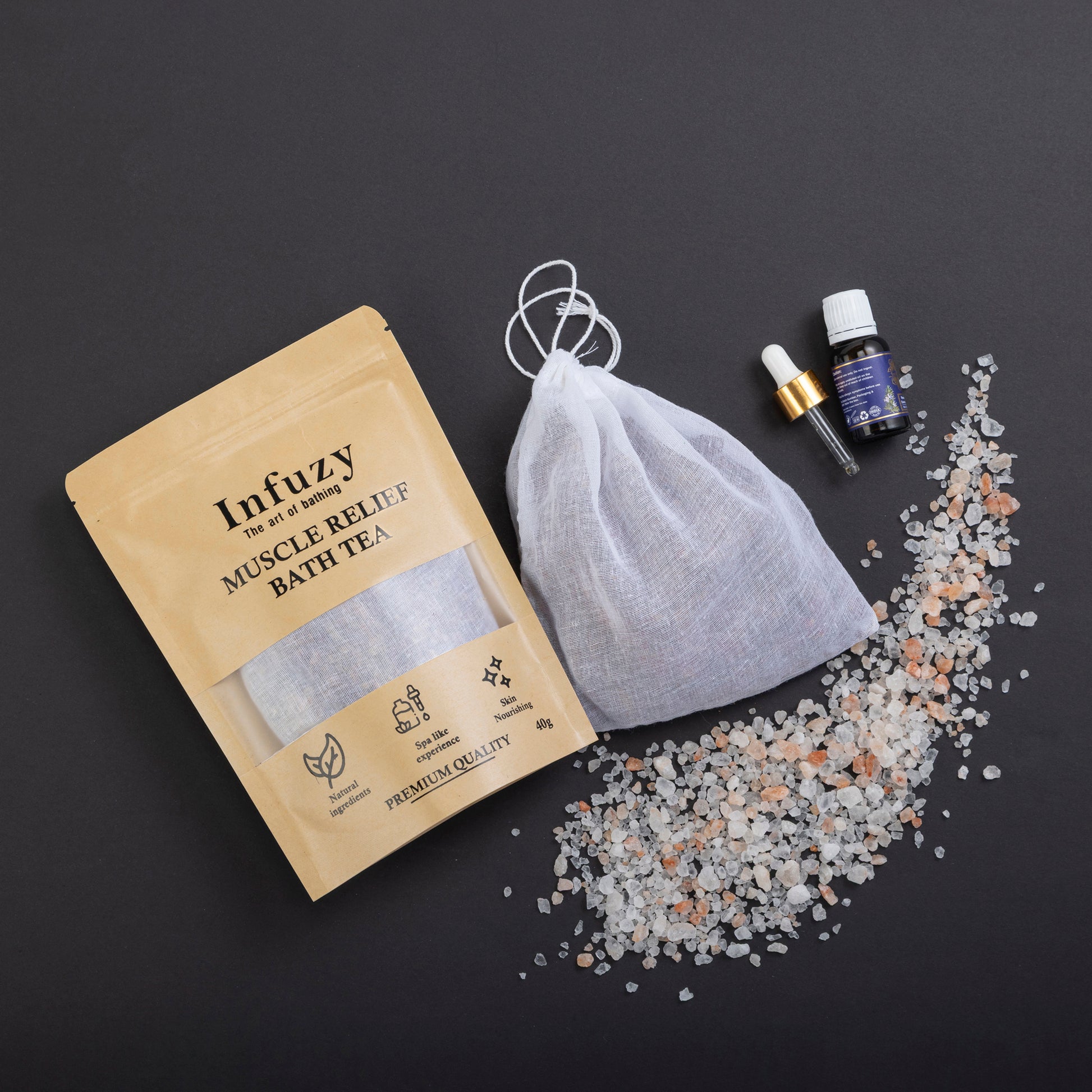 Infuzy muscle relief bath tea package with a drawstring bag and bath salts on a dark background