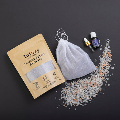 Infuzy muscle relief bath tea package with a drawstring bag and bath salts on a dark background