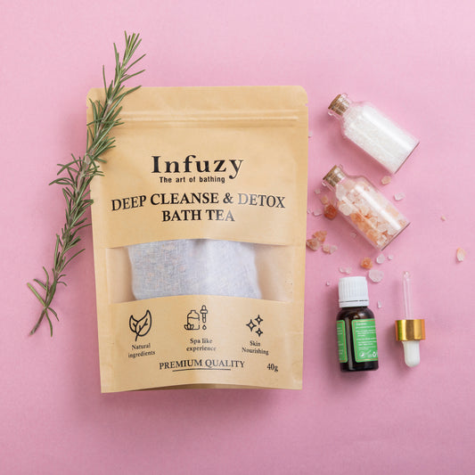 Packaging of 'Infuzy Deep Cleanse & Detox Bath Tea' with contents displayed including a bag of bath tea, Dead Sea salt, rosemary sprig, and essential oils.